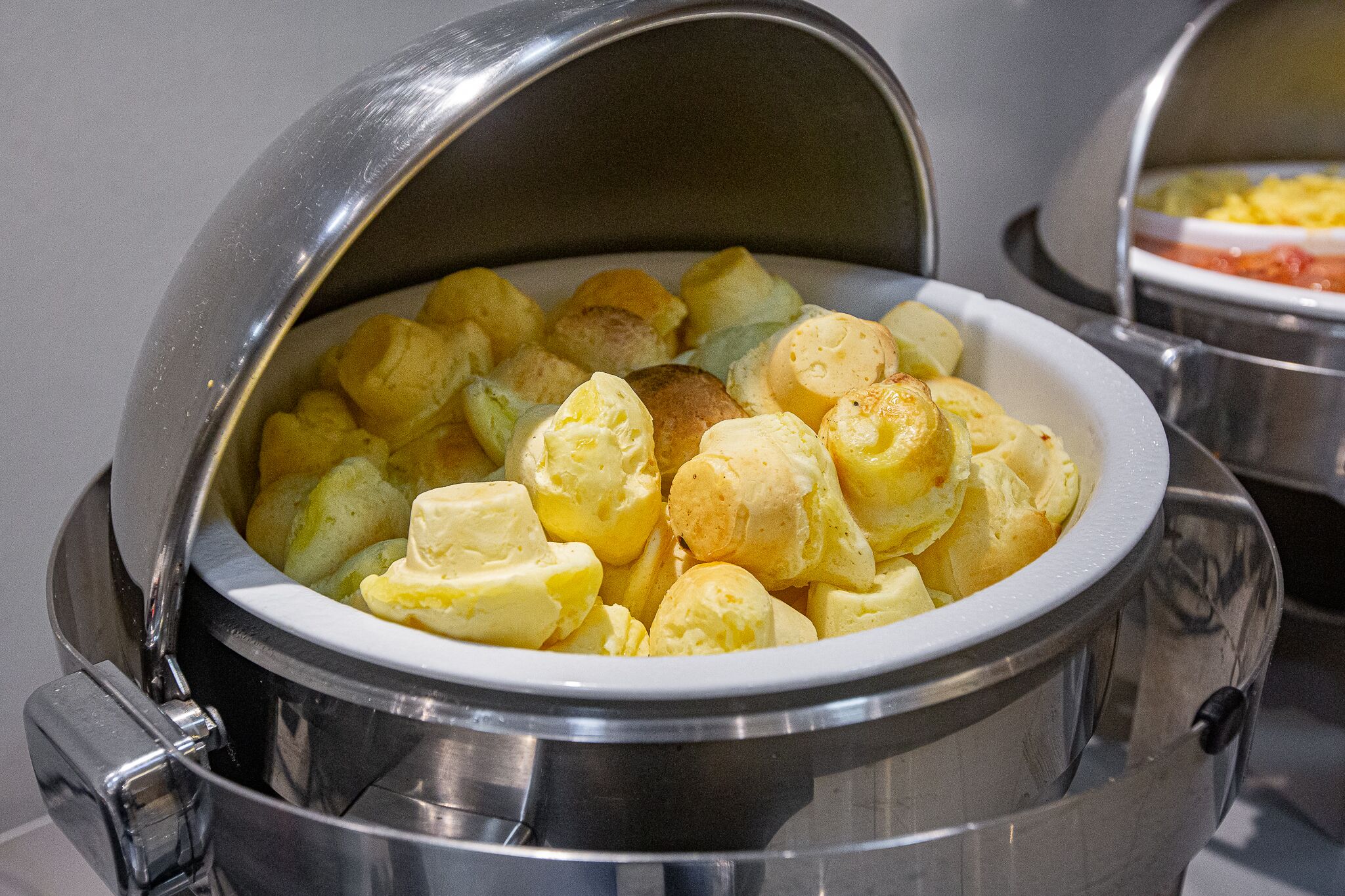 A buffet with a covered serving dish containing potatoes and other food items.