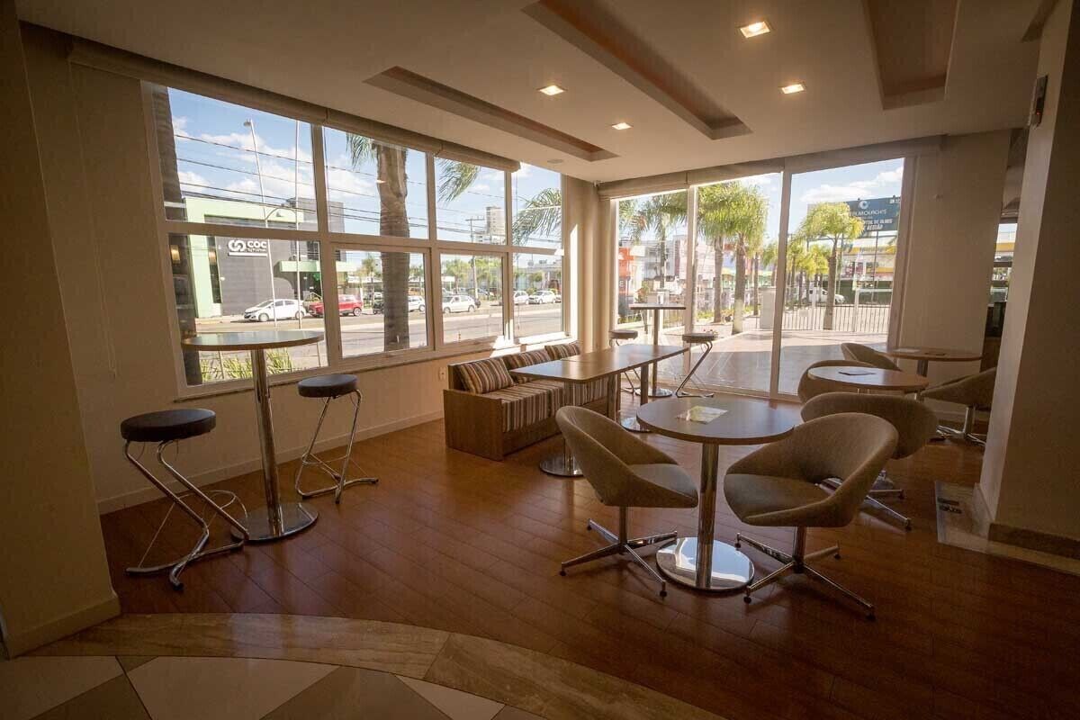 A modern interior with large windows, a round table, and bar stools.
