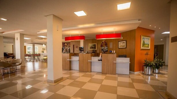 Una hall d'albergo con pavimento a scacchi, reception e un'area salotto.