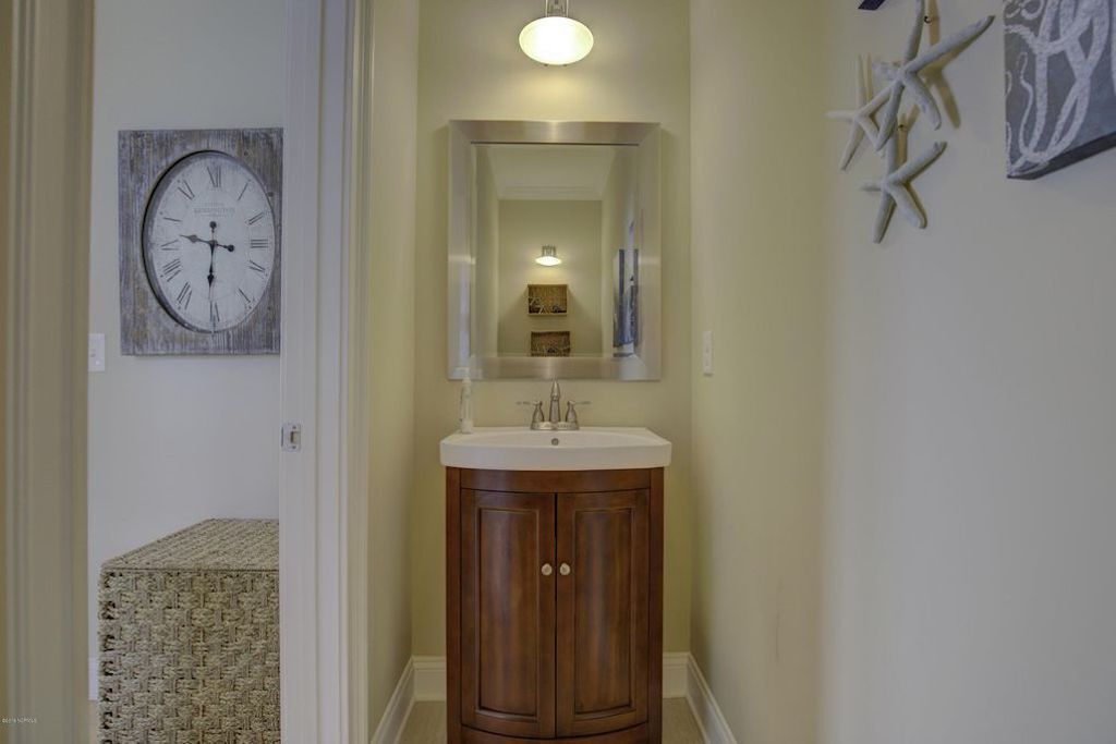 Un baño con tocador de madera, un espejo y un reloj de pared.