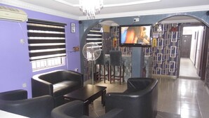 A living room with a TV, black leather sofas, a fan, and a bar area.