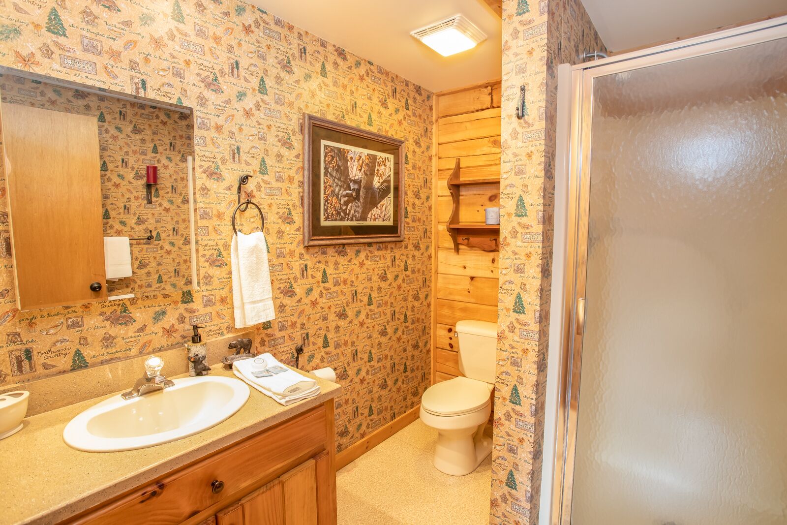 Un baño con tocador de madera, lavamanos, inodoro y zona de ducha.