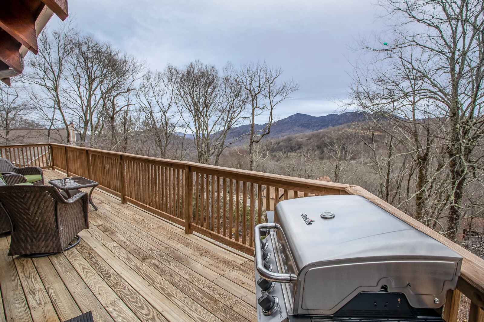 Eine Holzterrasse mit Grill und Gartenmöbeln.