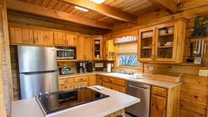 A modern kitchen with wooden cabinetry, stainless steel appliances, and a central island with seating.