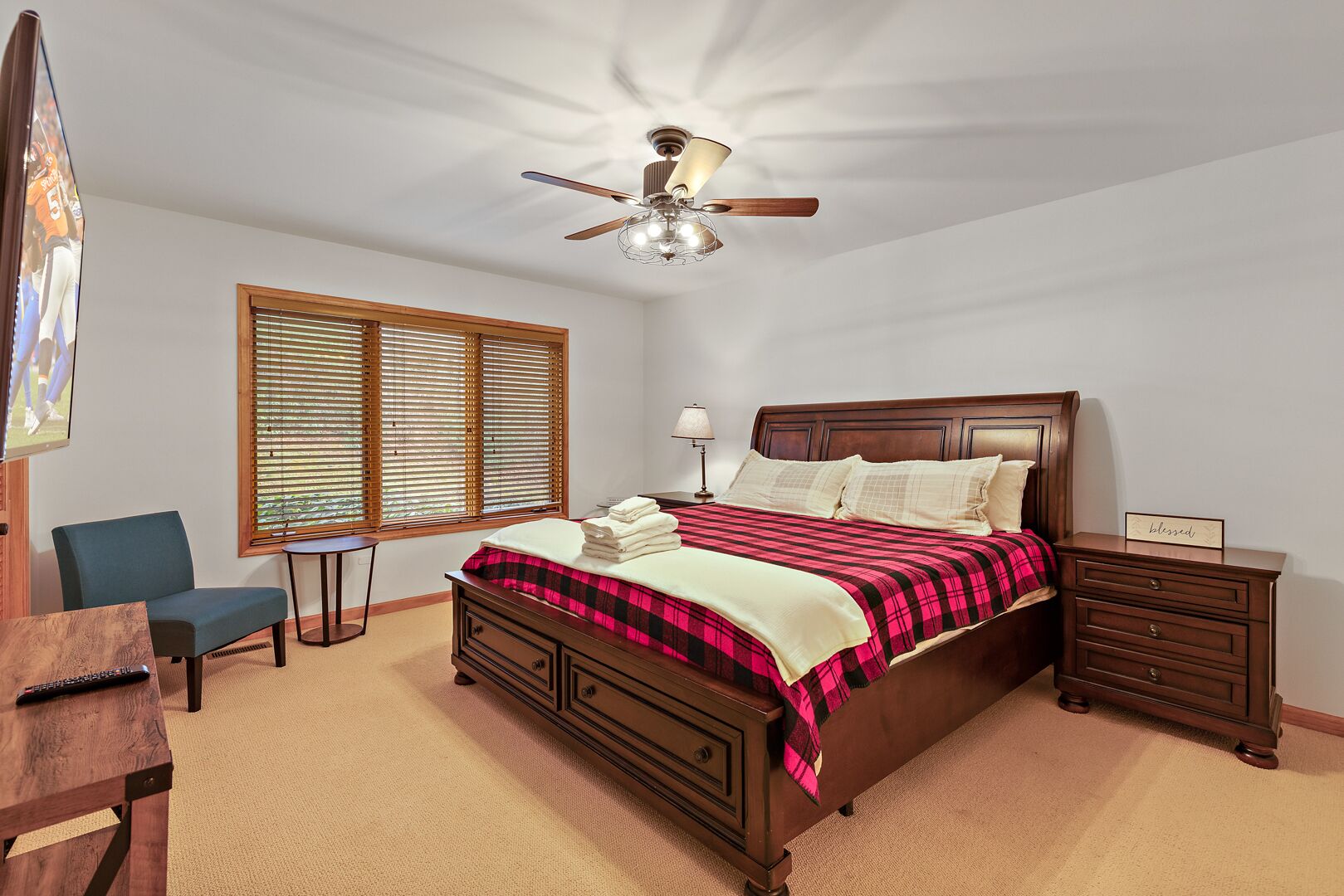 Ein Schlafzimmer mit einem hölzernen Bett, einem Deckenventilator, einem Schreibtisch und einem Stuhl.