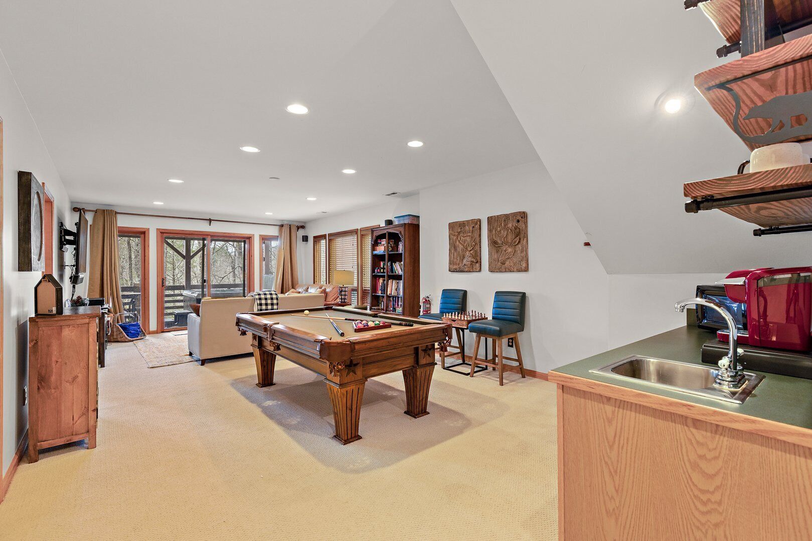 Een ruime kamer met een pooltafel, een bank en een boekenplank.