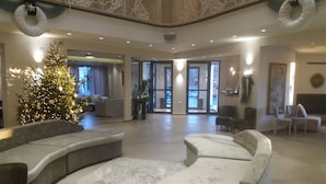 A spacious lobby with a Christmas tree, seating areas, and a view of the outside.