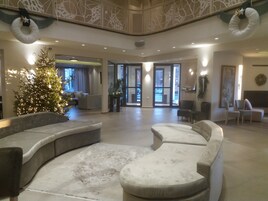 Un vestíbulo amplio con un árbol de Navidad, zonas de estar y vistas al exterior.