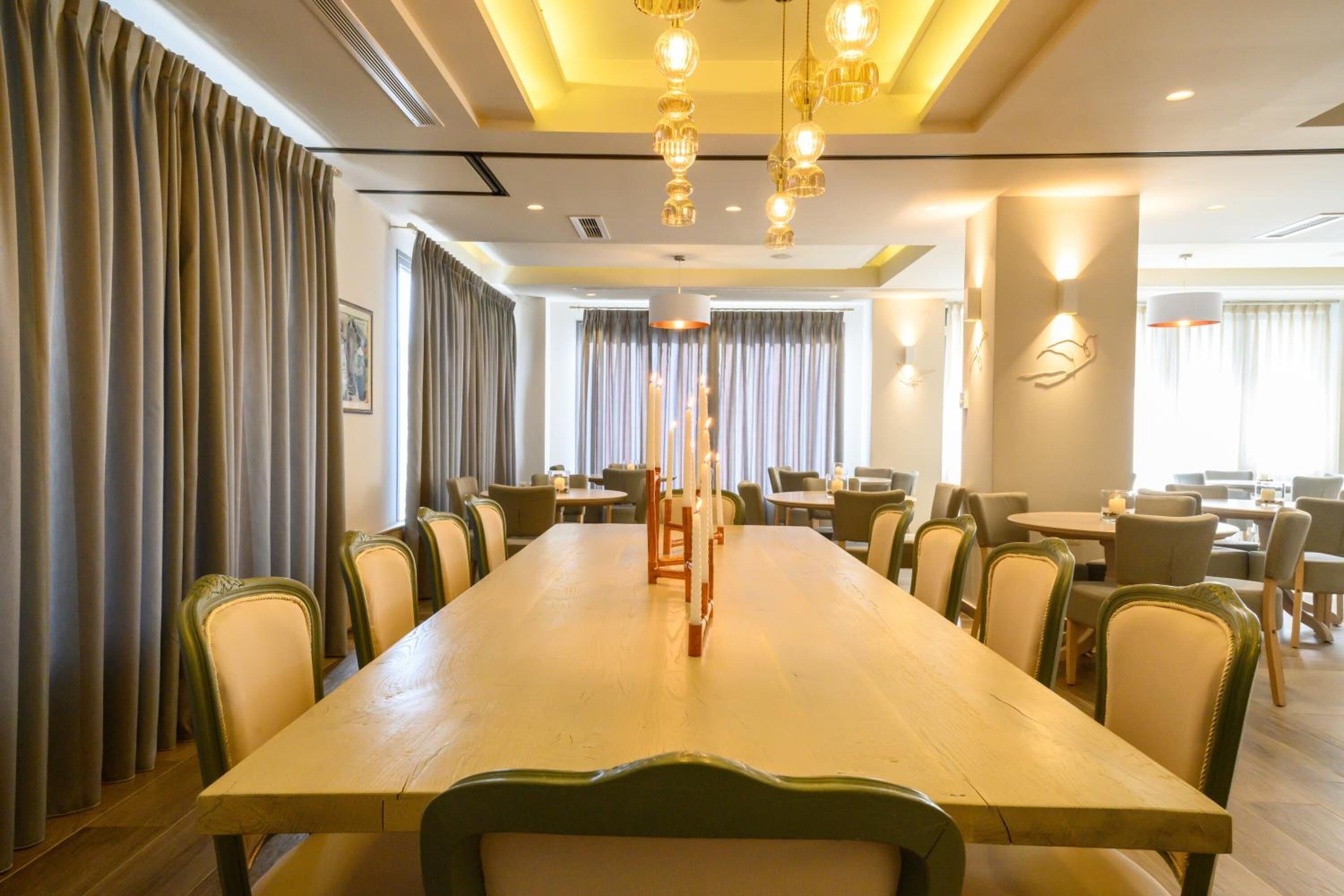 A conference room with a long table, chairs, and pendant lighting.