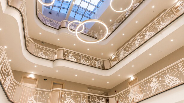 A multi-level atrium with ornate railings and circular light fixtures.