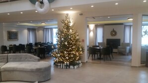 A spacious lobby with a large Christmas tree, seating areas, and a modern interior design.