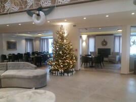 Un vestíbulo espacioso con un gran árbol de Navidad, zonas de estar y un diseño interior moderno.