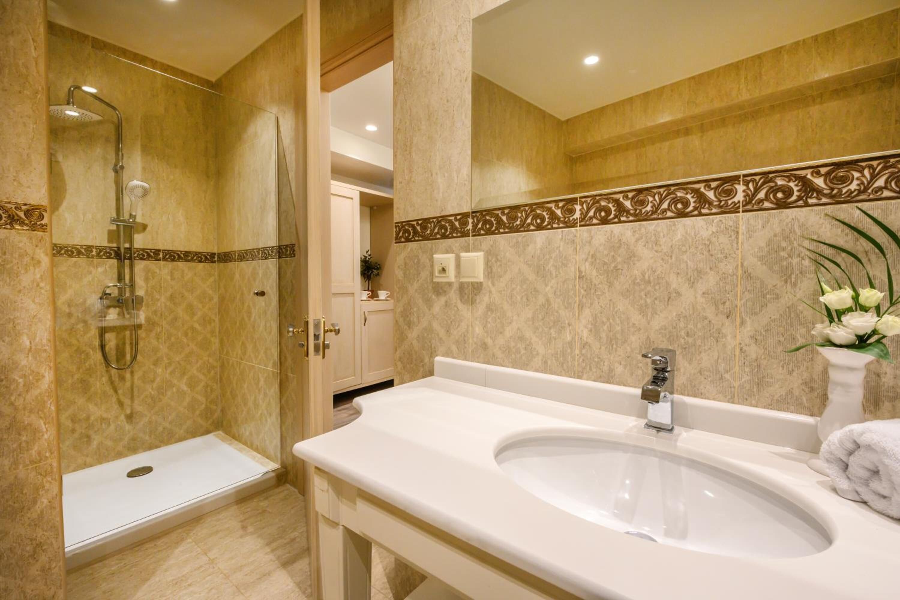 A bathroom with a large sink, a shower, and a mirror.