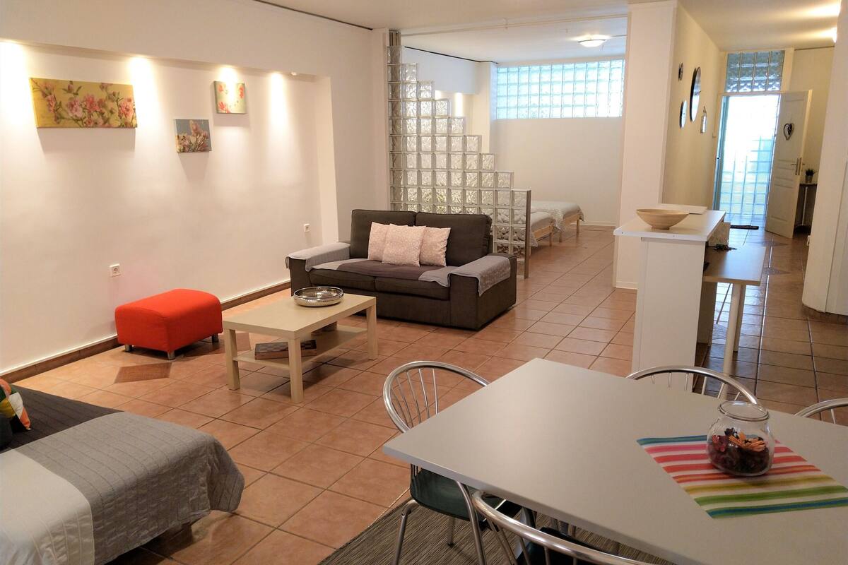 Un salon moderne avec un canapé, une table à manger et un coin cuisine visible au fond.