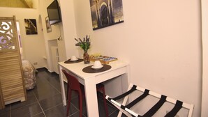 A small dining area with a white table, red chairs, a black and white striped chair, a vase with flowers, and a framed picture on the wall. - Dimora Giulietta Standard Apartment (Lecce)