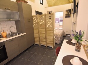 Cocina compacta con lavamanos, armarios y comedor con mesa y sillas.