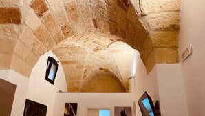 An interior with stone arches, a white door, and artwork on the walls. - Dimora Giulietta Standard Apartment (Lecce)