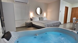Une chambre à coucher avec une grande baignoire, un lit avec des oreillers, une table de chevet et un miroir au mur.