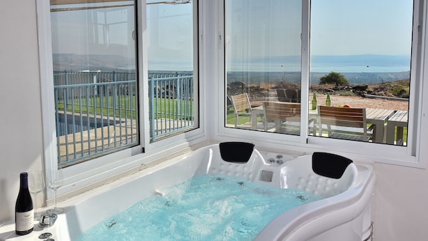 Une salle de bain avec une baignoire, une bouteille de vin et deux verres.