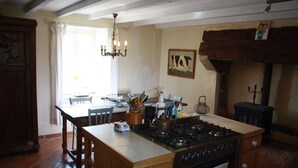 Een keuken met een centraal eiland, fornuis en een eethoek met stoelen en een tafel.
