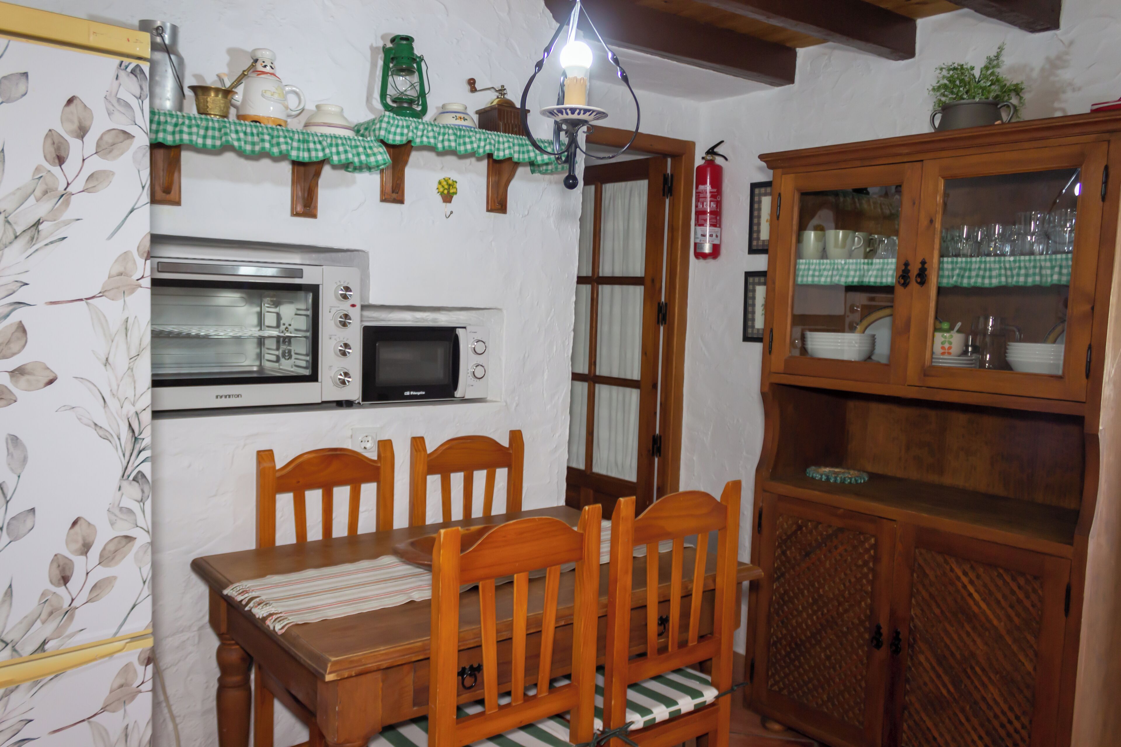 Eine Küche mit Holztisch, Stühlen, einer Mikrowelle, einem Herd und einem Schrank.