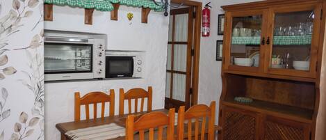 Eine Küche mit Holztisch, Stühlen, einer Mikrowelle, einem Herd und einem Schrank.