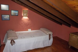 Une pièce comprenant un lit, une petite armoire et trois tableaux encadrés accrochés au mur.