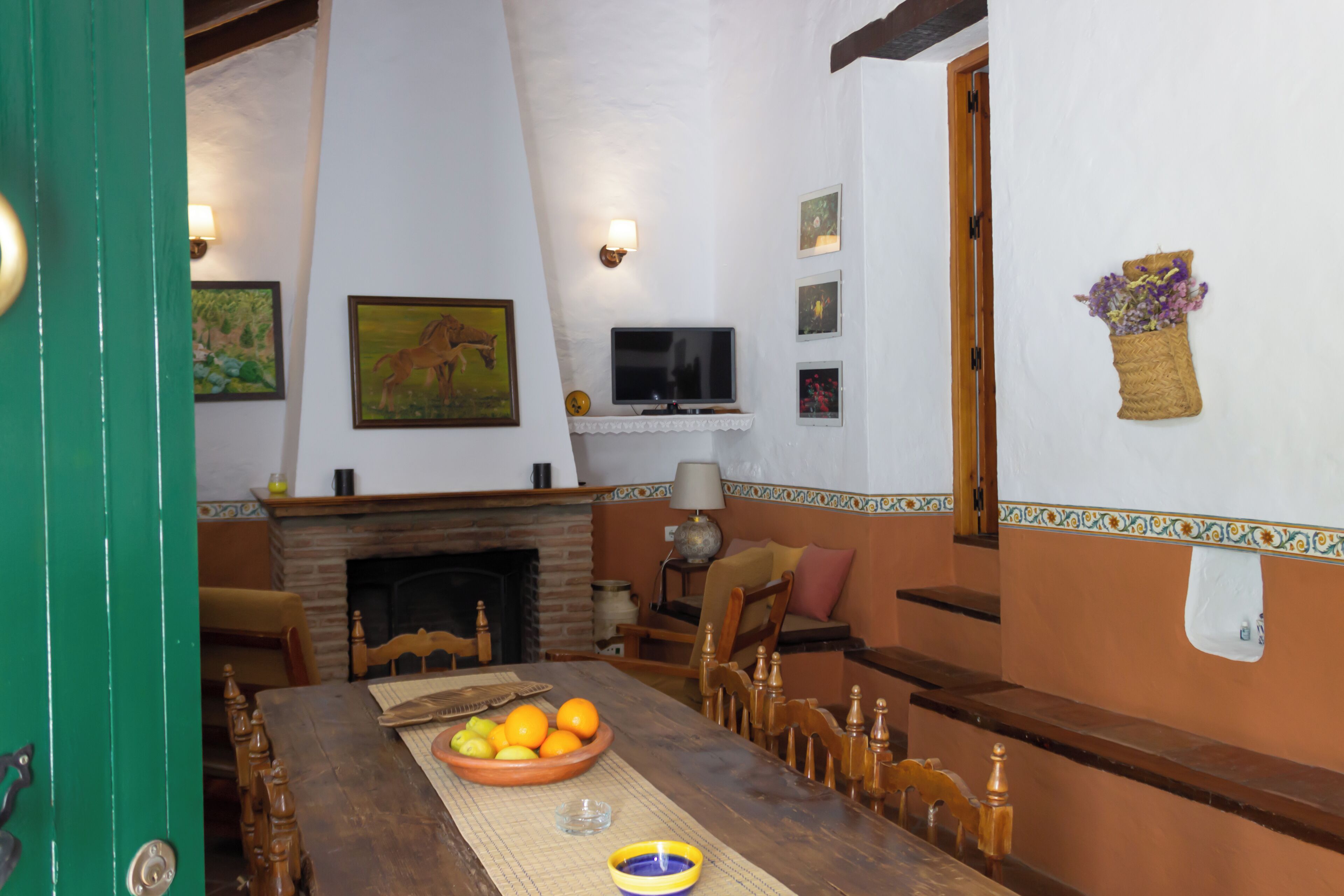 Una zona de comedor con una mesa de madera, un cuenco de fruta y una chimenea.