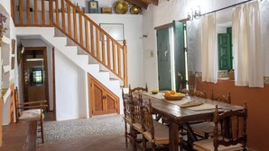 A dining area with a wooden table, chairs, and a staircase.