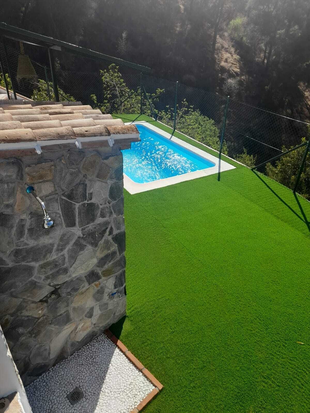 Een zwembad met kunstgras en een stenen constructie.