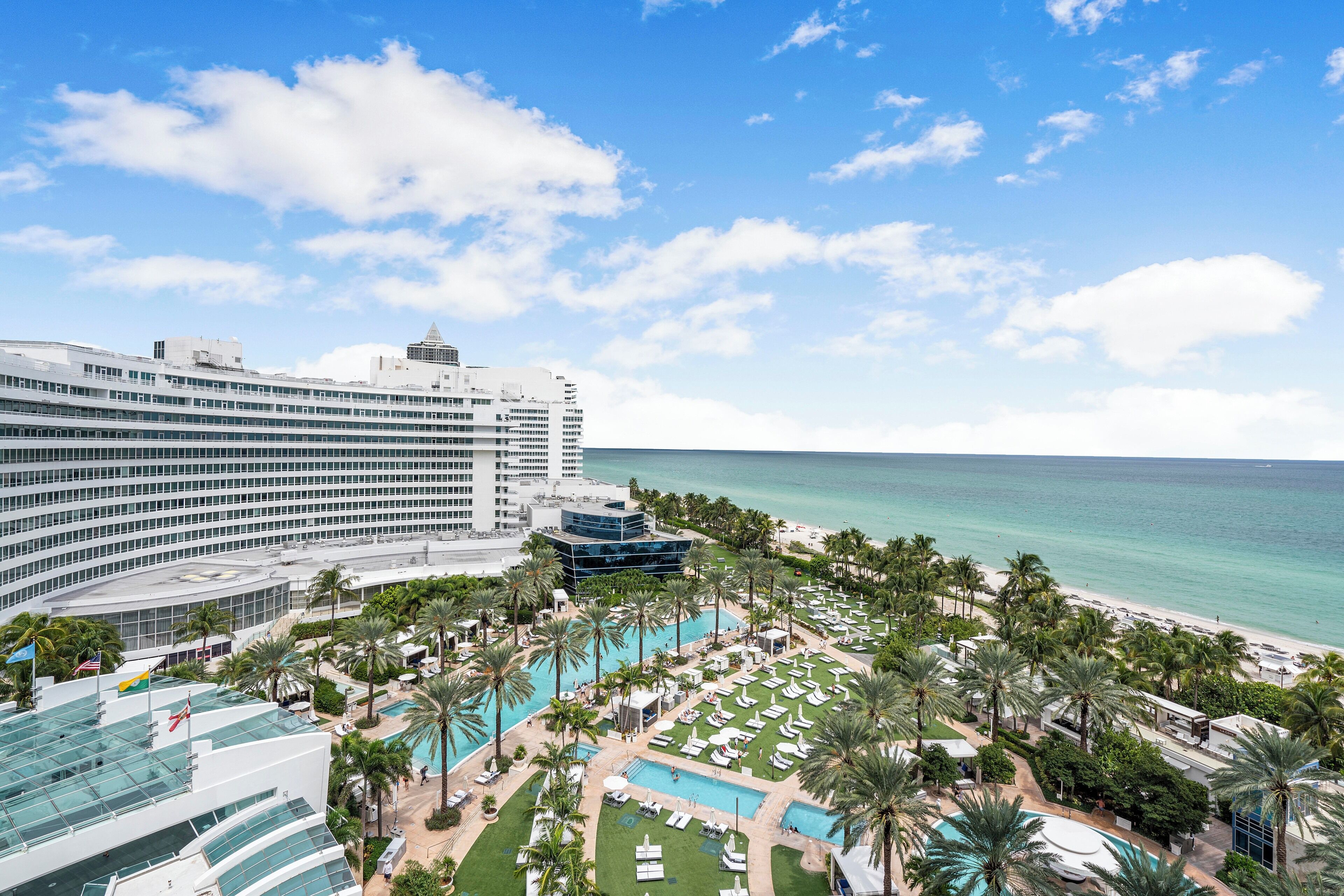 Un resort con una amplia zona de piscina, palmeras y vistas al océano.