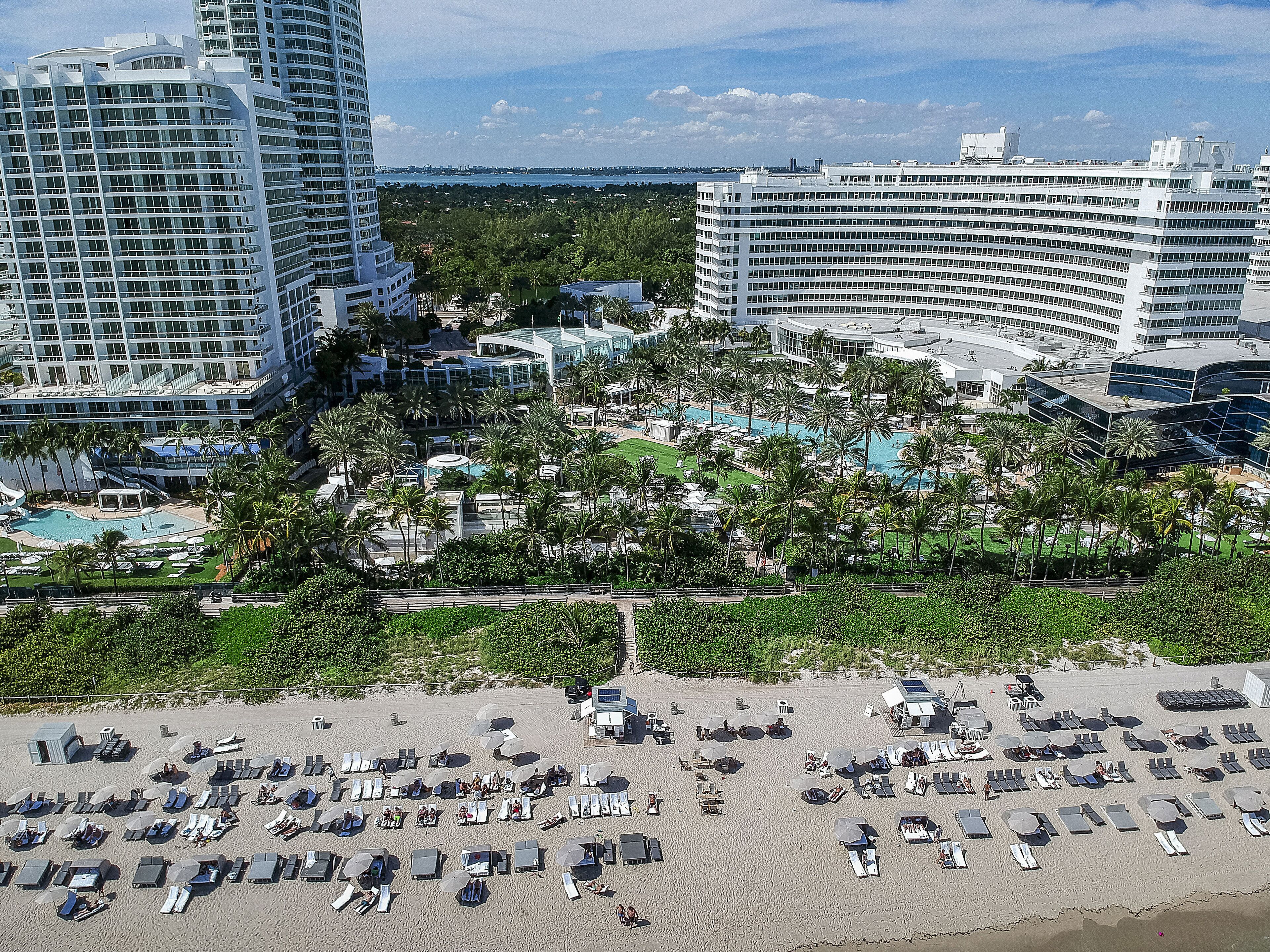 Un resort con varios edificios de gran altura, un amplio área de piscina y una playa con tumbonas.