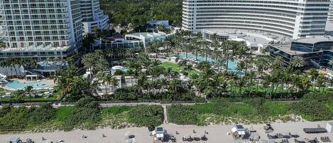 Un resort con varios edificios de gran altura, un amplio área de piscina y una playa con tumbonas.