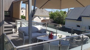 Terraza en la azotea con mesas y sillas al aire libre, una mesa y un paraguas grande.