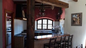 Una cocina con una isla central, sillas de madera, un ventanal y un microondas.