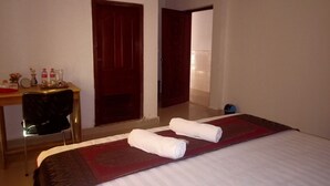 A hotel room with a bed, a desk with a chair, a door, and a small table with items on it. - The Crocodile villa (Siem Reap)