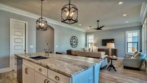 A spacious kitchen with a large island, pendant lights, and a ceiling fan.