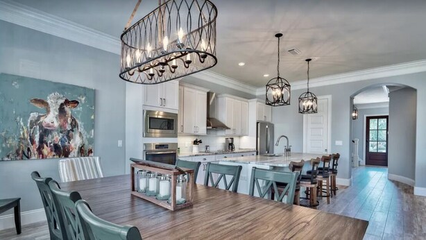 A spacious kitchen with wooden flooring, a central island, and modern appliances.