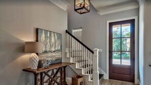A wooden console table with a lamp and decorative items, a staircase with white railings, and a door with a window view.