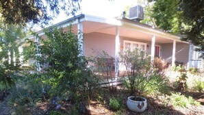 A house with a covered porch, surrounded by dense greenery and a garden area.