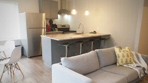 Een moderne keuken met een inbouw eiland, een grijze bank en een witte stoel.