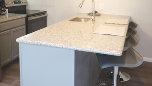 Een moderne keuken met een granieten aanrechtblad, roestvrijstalen apparatuur en een geïntegreerde spoelbak.
