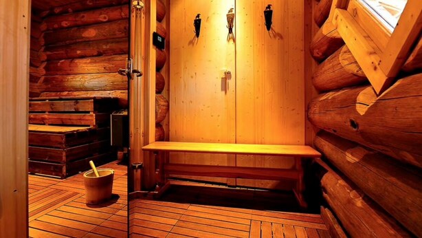 Una sauna de madera con bancos y un cubo.