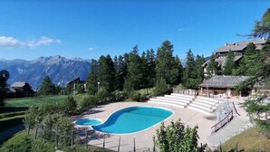 Una piscina con vistas a montañas, rodeada de árboles y edificios.