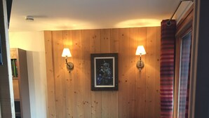 Una habitación acogedora con un sofá azul oscuro, un reposapiés y dos lámparas fijadas a la pared.