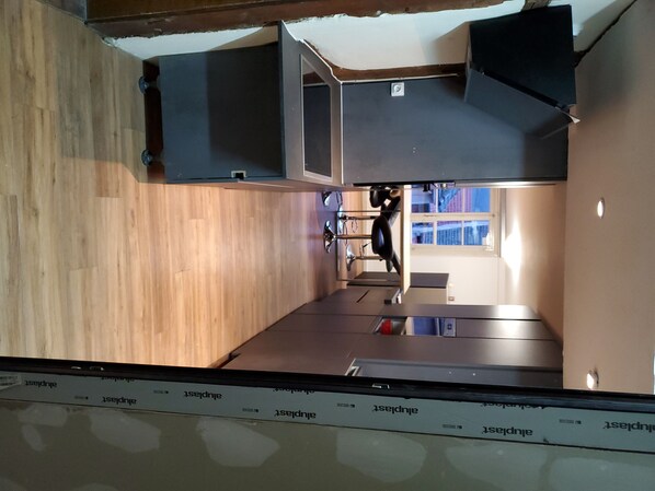 A modern kitchen with wooden flooring, built-in appliances, and a window providing natural light.