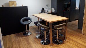A modern kitchen with a wooden table and bar stools, a black countertop, and a built-in oven.