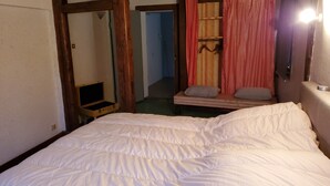 A bedroom with a large bed, wooden beams, a mirror, and a small table.