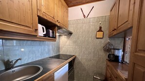 Una cocina compacta con armarios de madera, un lavamanos de acero inoxidable y un lavavajillas.