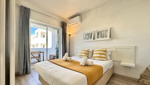 Une chambre d’hôtel avec un lit, un balcon et une vue sur les immeubles.